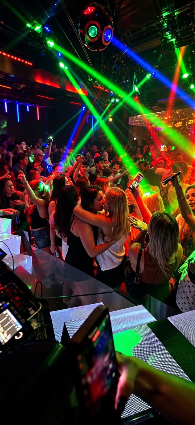 Dancers on a crowded floor under sweeping green laser beams
