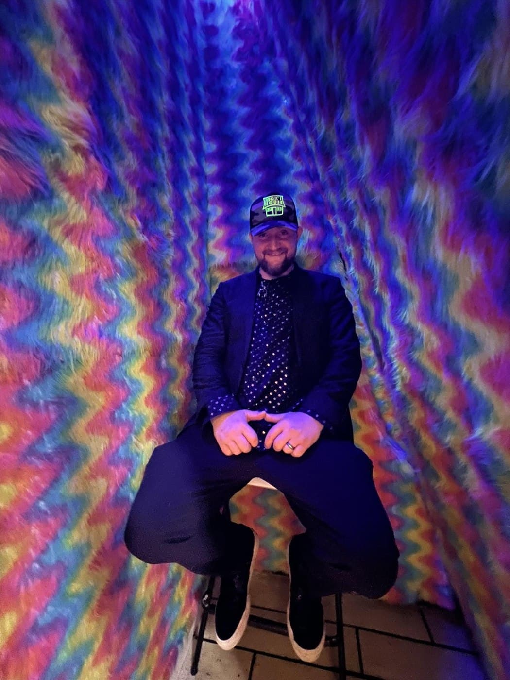 John Wayne seated in a colorful psychedelic room